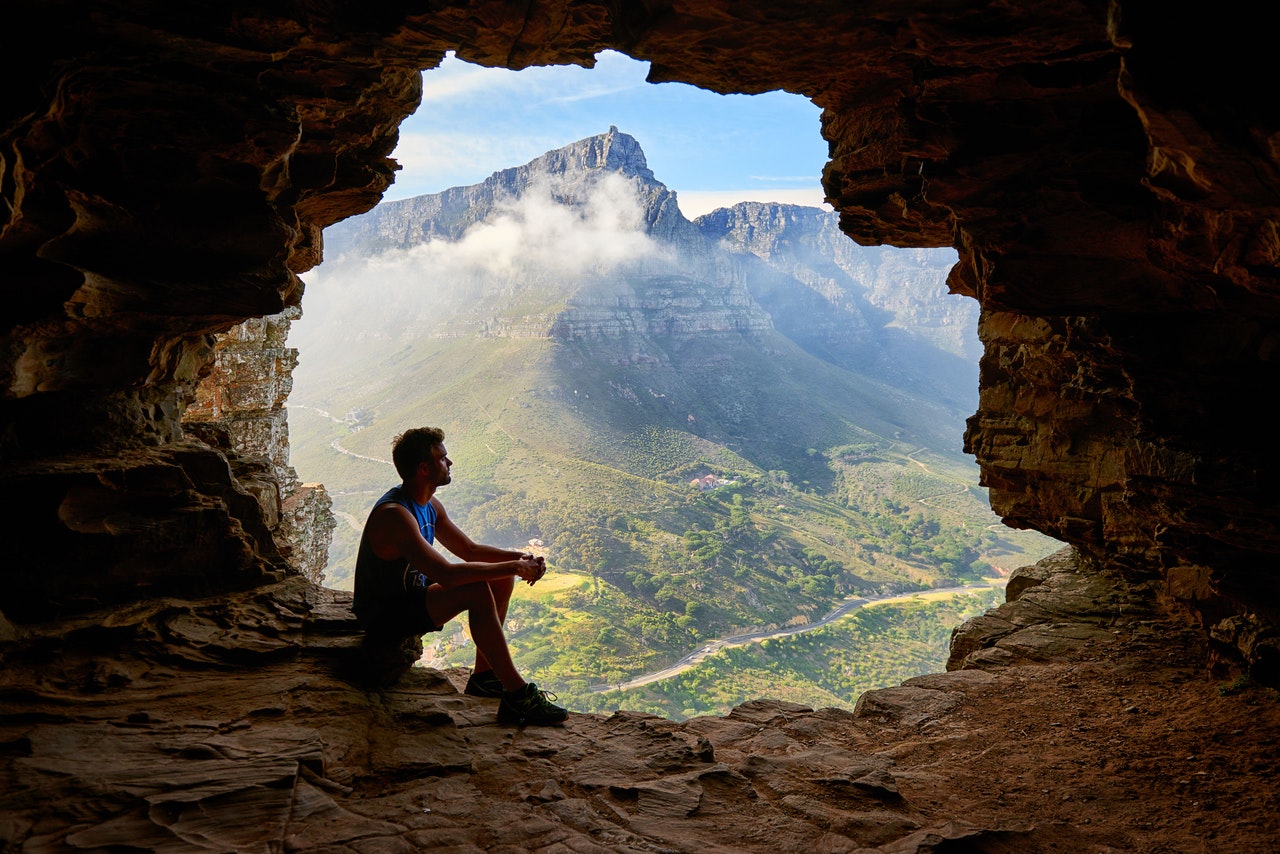 A person sitting in a cave overlooking a mountain